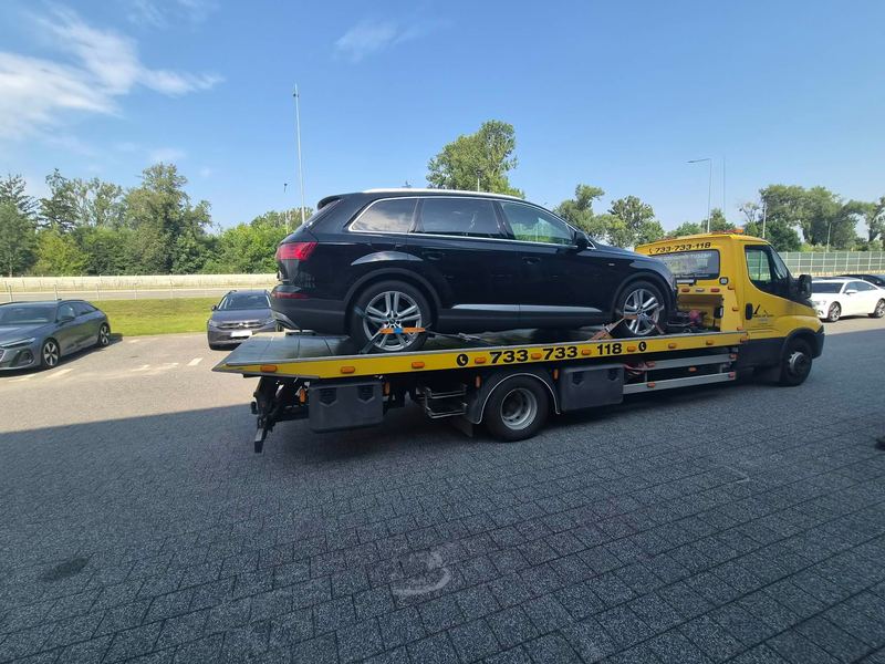 SUV bez widocznych uszkodzeń załadowany na lawecie stoi na miejskim parkingu, pomoc drogowa Tuszyn w akcji