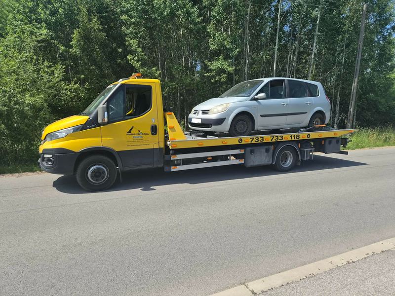 Laweta pomocy drogowej Tuszyn wioząca kompaktowy samochód osobowy po awarii drogą leśną