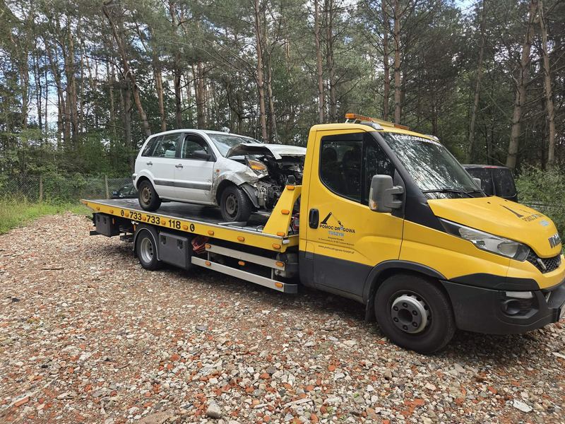 Pomoc drogowa Tuszyn odbiera lawetą rozbite po kolizji kompaktowe auto z leśnej, żwirowej działki