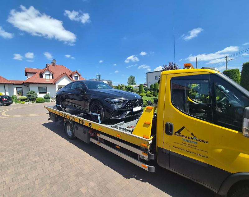 Mercedes coupé przewożony lawetą pomocy drogowej Tuszyn stoi na podjeździe posesji w słoneczny dzień