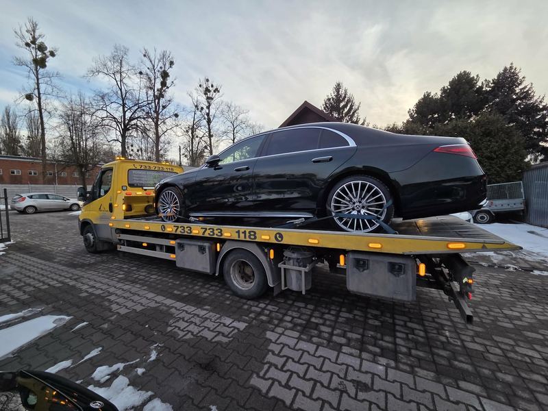 Elegancki sedan bez uszkodzeń na lawecie na zaśnieżonym placu firmy pomoc drogowa Tuszyn