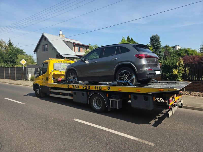 Laweta pomocy drogowej Tuszyn transportuje SUV-a spokojną ulicą osiedlową