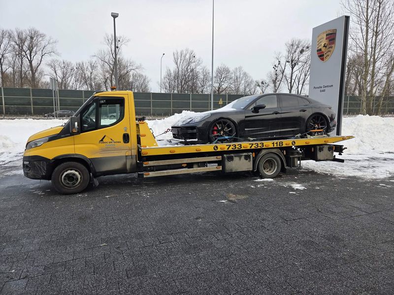 Sportowy sedan czeka na lawecie na ośnieżonym placu przed serwisem, pomoc drogowa Tuszyn