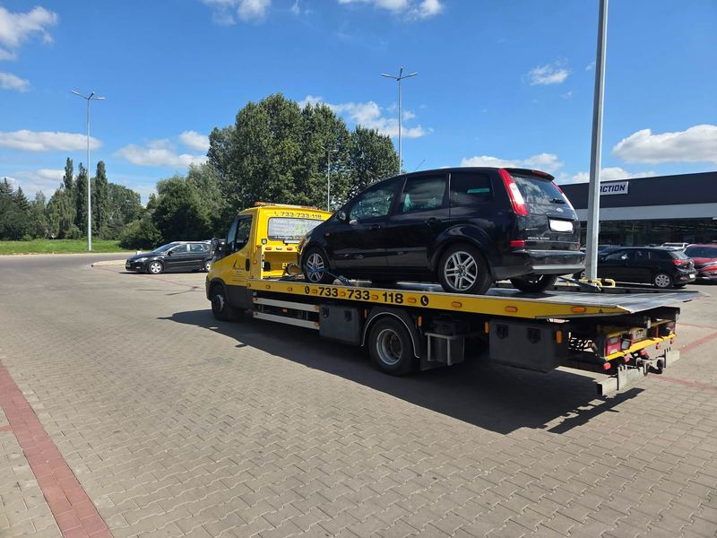 Laweta pomocy drogowej Tuszyn wywozi kombi z miejskiego parkingu przy salonie samochodowym