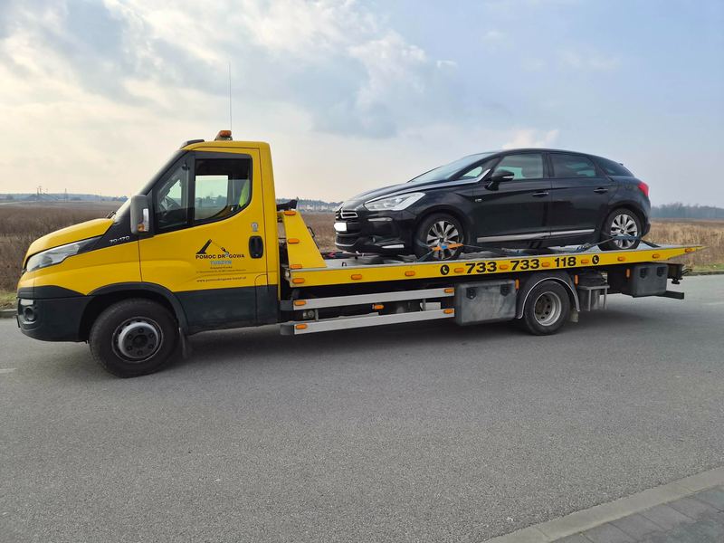 Laweta z pomocy drogowej Tuszyn przewozi sprawny samochód osobowy hatchback ulicą osiedlową