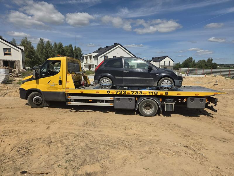 Laweta pomocy drogowej Tuszyn transportuje sprawny samochód osobowy hatchback na placu budowy osiedla domów