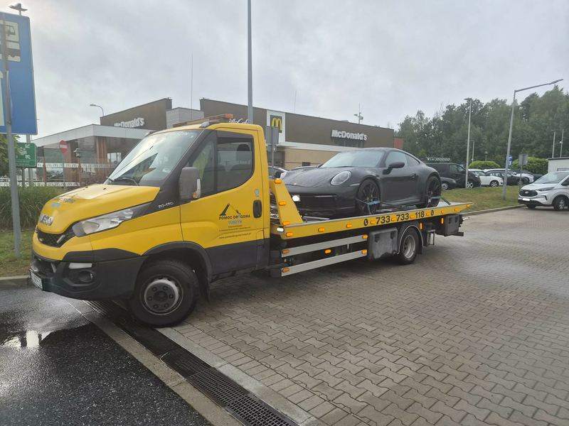 Sportowe coupe na lawecie na parkingu przy restauracji w deszczowy dzień, obsługuje pomoc drogowa Tuszyn