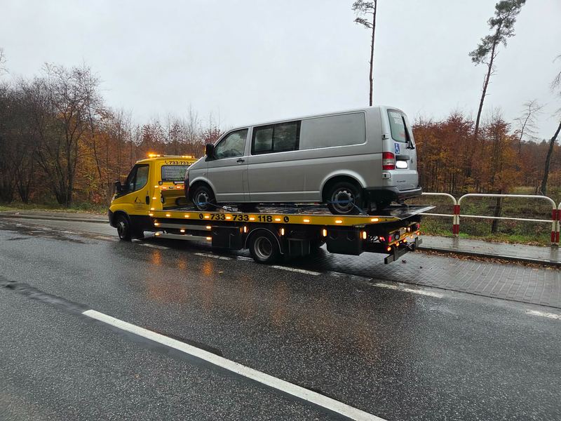 Laweta pomocy drogowej Tuszyn transportuje bus dostawczy mokrą jesienną drogą w deszczu