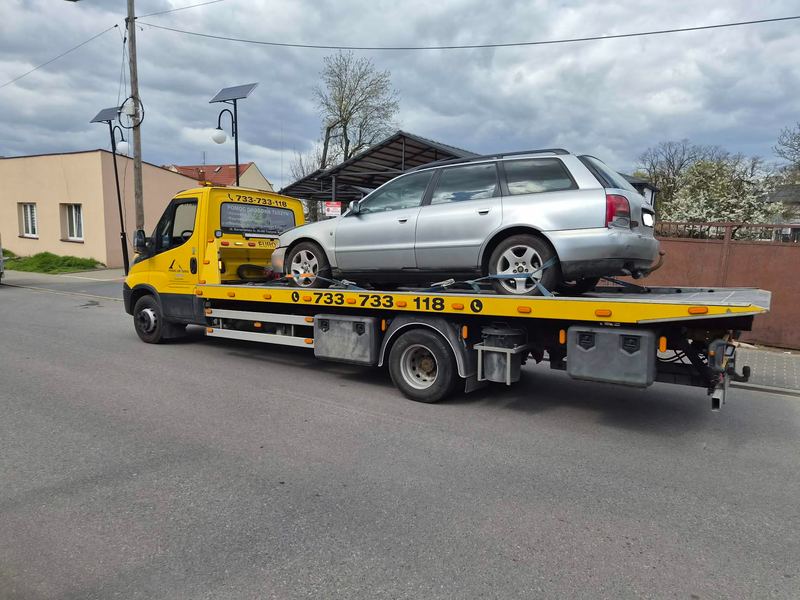 Laweta transportuje kombi ulicą miasta w pochmurny dzień, pomoc drogowa Tuszyn
