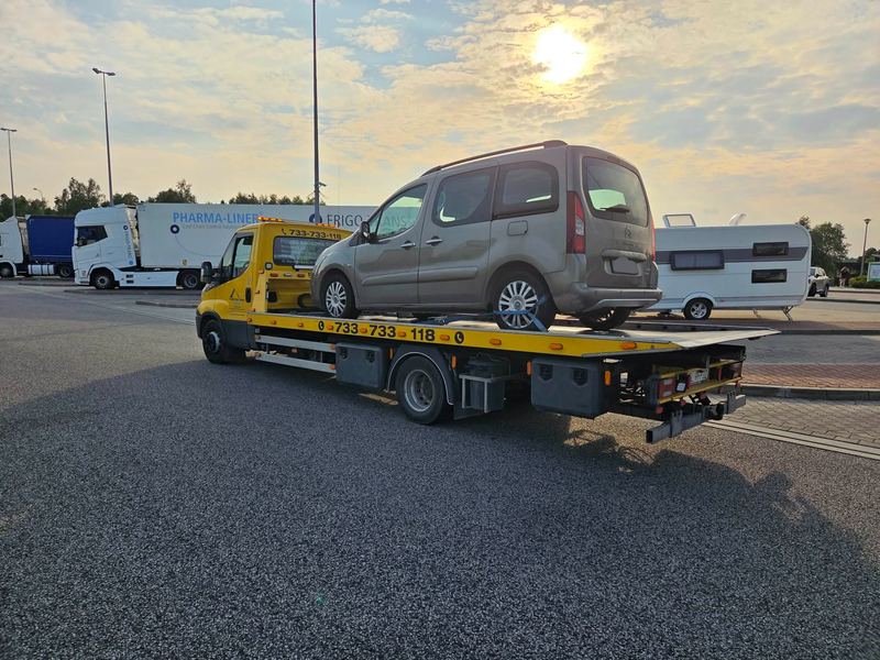 Laweta z pomocy drogowej Tuszyn wiezie kombivana na parking o zachodzie słońca