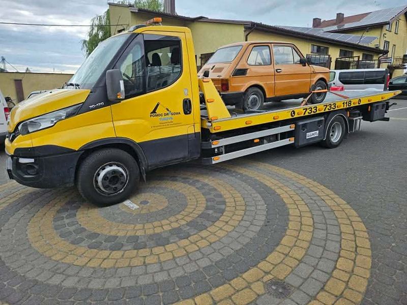 Laweta pomocy drogowej Tuszyn przewozi mały zabytkowy samochód osobowy na miejskim parkingu
