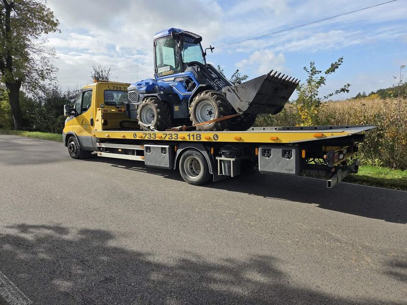 Laweta transportuje ładowarkę kołową drogą wśród pól w słoneczny jesienny dzień pomoc drogowa Tuszyn