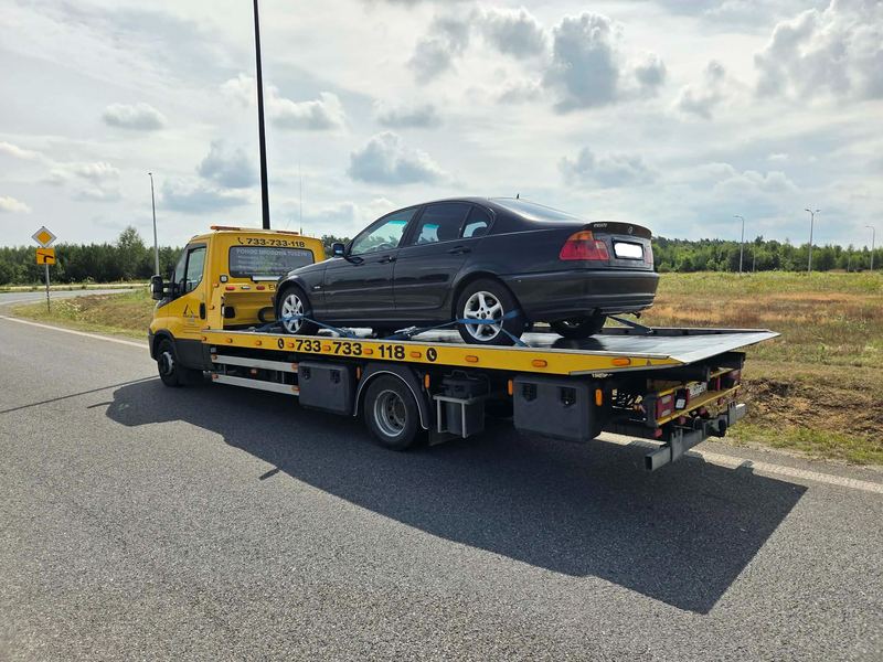 Sedan przewożony na lawecie pomocy drogowej Tuszyn zatrzymanej na poboczu drogi poza miastem