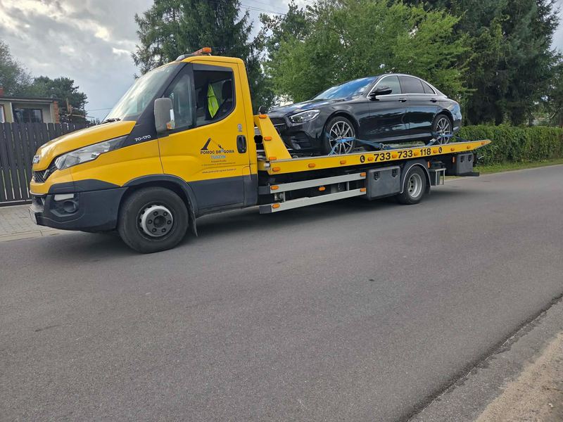 Elegancki sedan załadowany na lawetę pomocy drogowej Tuszyn stojącą przy ulicy osiedlowej