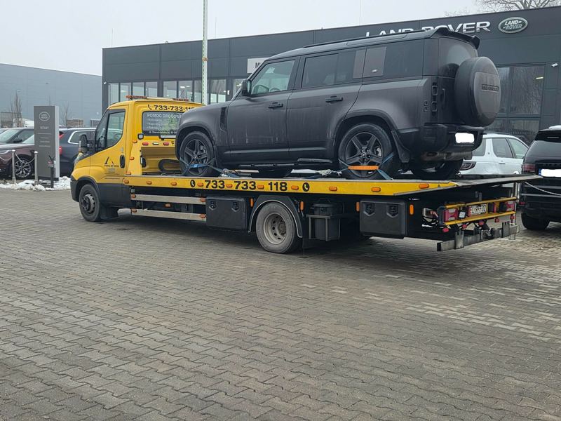 Duży SUV 4x4 bez uszkodzeń na lawecie przed salonem dealera zimą, laweta pomocy drogowej Tuszyn
