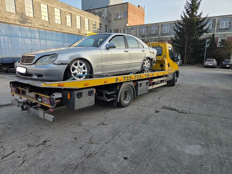 Laweta transportuje sedan z rozbitym przodem po kolizji na zakładowym placu, pomoc drogowa Tuszyn