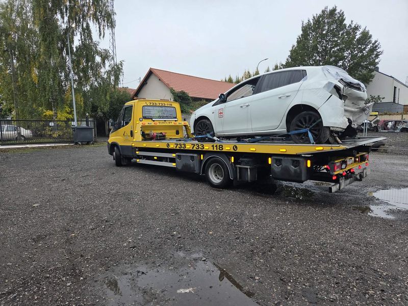 Pomoc drogowa Tuszyn transportuje lawetą rozbite w poważnym wypadku auto osobowe na żwirowym placu