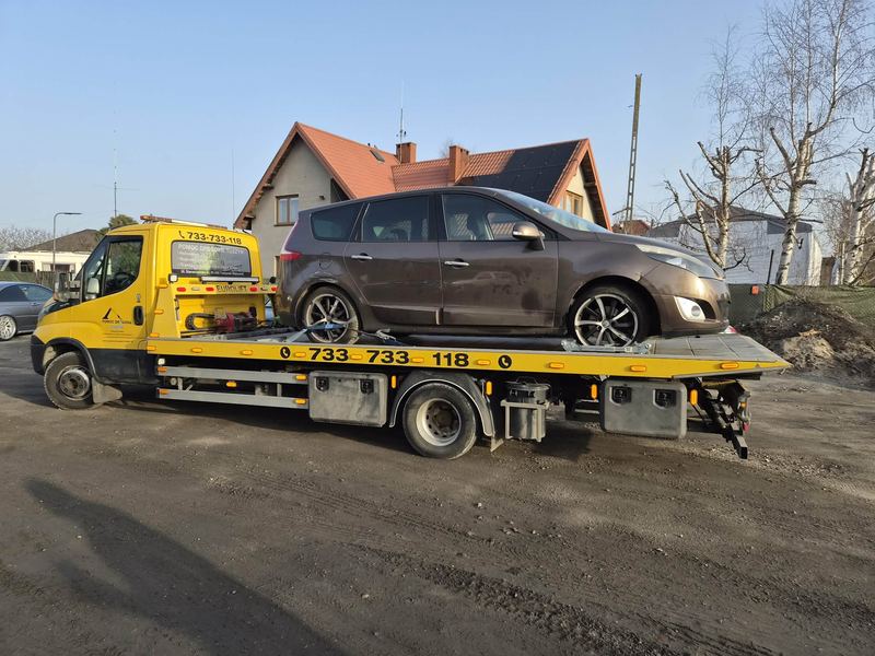 Kompaktowy van stoi na lawecie transportowej na posesji pod domem jednorodzinnym