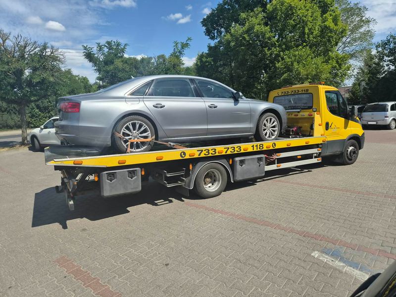Sedan spoczywa na lawecie Pomocy Drogowej Tuszyn na miejskim parkingu w słoneczny dzień