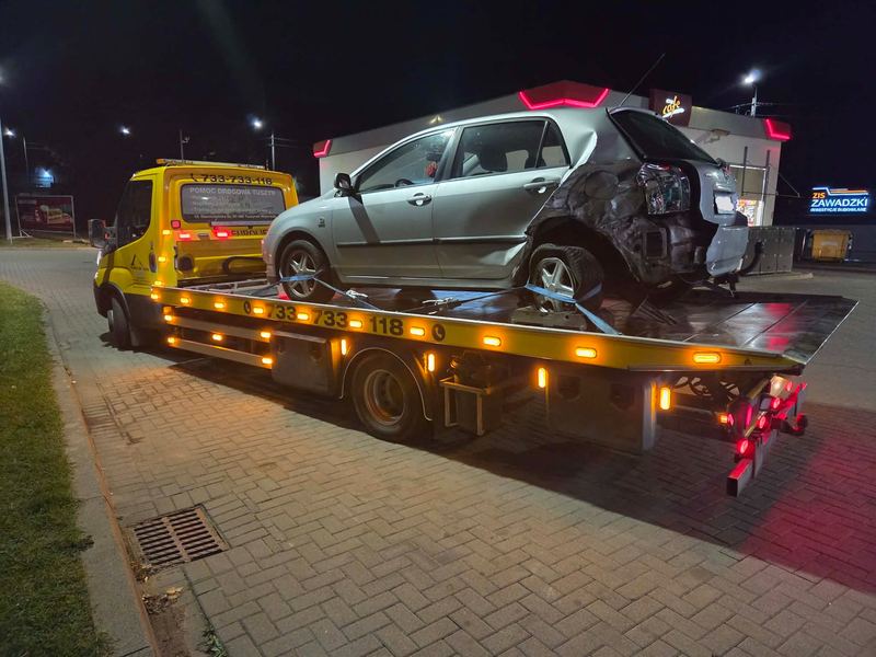 Rozbity z tyłu samochód osobowy transportowany nocą lawetą pomocy drogowej Tuszyn przy stacji paliw