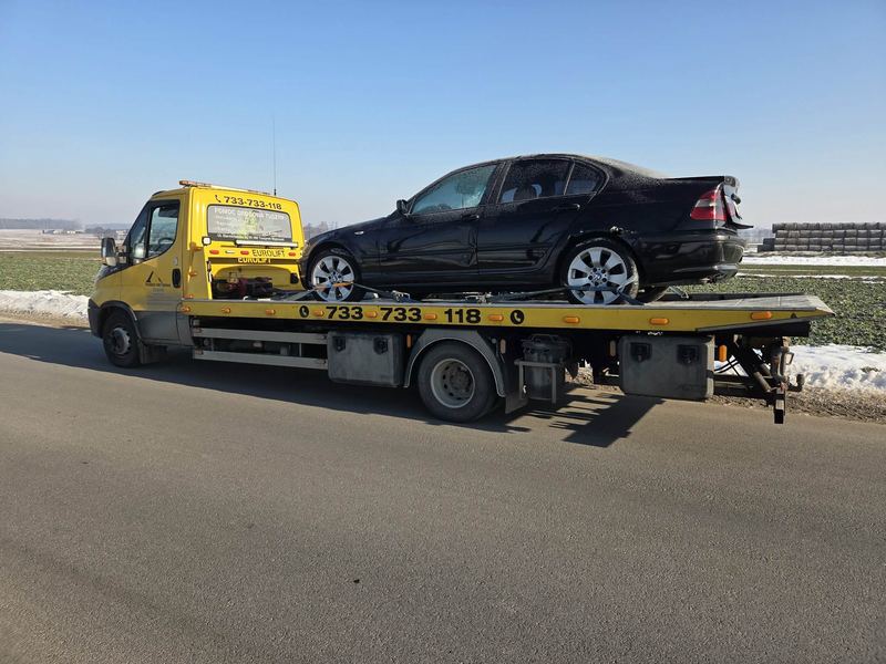 Sedan wymagający pomocy drogowej jedzie na lawecie przez ośnieżone pola zimą