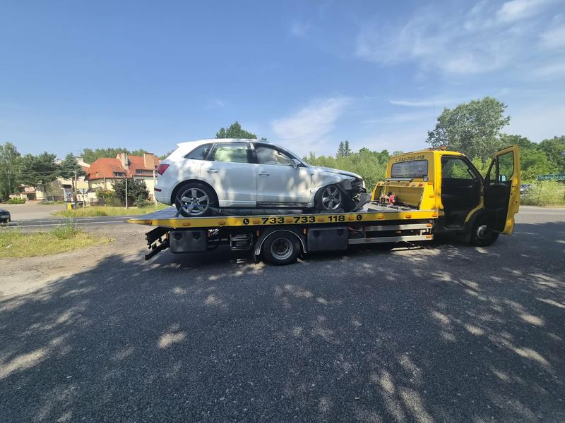 Kompaktowy SUV z rozbitym przodem stoi na lawecie pomocy drogowej Tuszyn przy skrzyżowaniu w słoneczny dzień