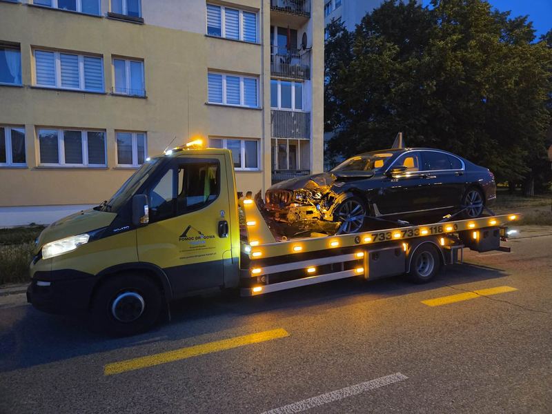 Poważnie uszkodzony z przodu samochód osobowy na lawecie wieczorem przy bloku mieszkalnym w mieście